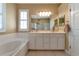 Bright bathroom featuring white vanity, soaking tub, and neutral-toned walls at 616 Misty Pond Ct, Bradenton, FL 34212