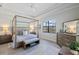 Elegant primary bedroom with a canopy bed, tray ceiling, and ample natural light from the screened window at 7130 Whittlebury Trl, Bradenton, FL 34202