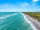 Aerial view of coastline with ocean waves and beach at 108 Corte Del Rosa, Venice, FL 34285