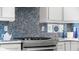 Modern kitchen with white cabinets, stainless steel appliances and blue mosaic backsplash at 108 Corte Del Rosa, Venice, FL 34285