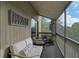 Screened balcony with white outdoor sofa, chairs, plants, and decorative wall hanging at 109 Woodland Pl, Osprey, FL 34229