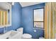 Blue bathroom with white vanity, toilet, and shower with a patterned curtain at 109 Woodland Pl, Osprey, FL 34229