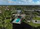 An aerial view showcasing the pool, tennis courts, and surrounding buildings at 109 Woodland Pl, Osprey, FL 34229