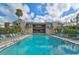 Community pool with a view of the condo building, lounge chairs, and trees at 109 Woodland Pl, Osprey, FL 34229