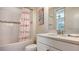 Clean bathroom with flamingo-themed shower curtain, white vanity, and tiled walls at 12667 Sorrento Way, Bradenton, FL 34211