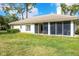 Home exterior featuring a spacious backyard with lush greenery and an enclosed sunroom at 2960 Sandringham Pl, Sarasota, FL 34235