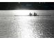 Silhouetted view of two rowers on a lake with sun-glittered water, creating a serene atmosphere at 2960 Sandringham Pl, Sarasota, FL 34235