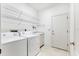 Well-lit laundry room featuring washer, dryer, wire shelving, and tile flooring at 2960 Sandringham Pl, Sarasota, FL 34235