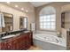 Main bathroom featuring dual vanities, a jetted tub, glass shower, and natural light at 4875 Wood Pointe Way, Sarasota, FL 34233