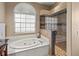 Main bathroom with a jetted tub, separate glass shower, and window view at 4875 Wood Pointe Way, Sarasota, FL 34233