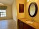 Bathroom vanity with granite countertop, dark wood cabinets, an oval mirror, and a window in the room at 5405 Fair Oaks St # 5405, Bradenton, FL 34203