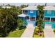 Two-story blue home with gray roof, paved driveway, and lush landscaping at 7007 Holmes Blvd, Holmes Beach, FL 34217