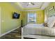 Bright green bedroom with wood-look floors, white bed and window with backyard view at 1256 Napoleon Rd, North Port, FL 34288