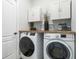 Laundry room with white cabinets, wood countertop, front-loading washer and dryer at 1256 Napoleon Rd, North Port, FL 34288