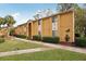 Building exterior with yellow stucco, landscaping, and a walkway at 1825 Parakeet Way # 503, Sarasota, FL 34232