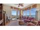 Living area with a red leather sofa, ceiling fan, and balcony access at 2050 Benjamin Franklin Dr # B603, Sarasota, FL 34236
