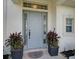 Light blue front door with sidelights and potted plants at 2112 Calusa Lakes Blvd, Nokomis, FL 34275