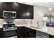 Modern kitchen with dark cabinets, granite countertops, and stainless steel appliances at 4905 Avila Lakes Dr, Wimauma, FL 33598