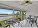 Relaxing screened porch with wicker table and chairs overlooking the water at 6029 E Peppertree Way # 116, Sarasota, FL 34242