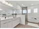 Modern bathroom with dual sinks, a soaking tub, and a glass-enclosed shower at 8007 Nevis Run, Bradenton, FL 34202