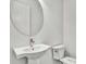 Modern powder room with a pedestal sink, round mirror, and white toilet at 8007 Nevis Run, Bradenton, FL 34202