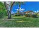 Large backyard with mature trees and a view of the home's exterior at 114 Fieldstone Dr, Venice, FL 34292