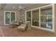 A covered back patio with sliding doors, wicker furniture, and brick floors at 114 Fieldstone Dr, Venice, FL 34292