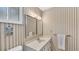 Clean bathroom with vertical striped wallpaper and white vanity at 1305 Glen Oaks E Dr # 130, Sarasota, FL 34232