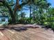 Large backyard with a wooden deck, lush trees, and a grassy area at 2724 Ashton Rd, Sarasota, FL 34231