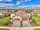 Aerial view of a home with tile roof, three-car garage, and landscaped yard at 27475 Janzen Ct, Englewood, FL 34223