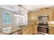 Kitchen with granite countertops, stainless steel appliances, light wood cabinets, and a breakfast bar at 4304 Camino Madera, Sarasota, FL 34238