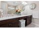 This bathroom features a double vanity, granite countertops, dark wood cabinets and stylish clocks on the walls at 4925 Surfside Cir, Bradenton, FL 34211