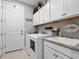 Well-lit laundry room featuring modern appliances, white cabinets, and a granite countertop at 4925 Surfside Cir, Bradenton, FL 34211