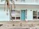 Exterior view of a unit's entrance with a teal door, window, and landscaping at 5055 N Beach Rd # 106, Englewood, FL 34223