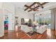 Elegant living room with hardwood floors, beamed ceiling, sliding glass doors, and comfortable white leather seating at 609 Colonial Bay Dr, Nokomis, FL 34275