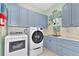 Laundry room with washer, dryer, and light blue cabinets at 6809 Belmont Ct, Lakewood Ranch, FL 34202