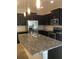 Modern kitchen with granite island, dark cabinetry, and stainless steel appliances at 8620 Ice Wine St, Sarasota, FL 34238