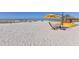 Beach scene with yellow umbrella, hammock, kayaks, and tiki hut on the sand at 915 Seaside Dr # 613 Weeks 4-5, Sarasota, FL 34242