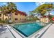 Well-maintained community pool with mature shade trees and adjacent cabana with a red roof and white trim at 207 Rubens Dr # D, Nokomis, FL 34275