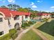 Condo complex with a red tile roof and mature tropical landscaping near community pool at 207 Rubens Dr # D, Nokomis, FL 34275