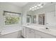 Bright bathroom with double sinks, a tub, and a window with garden views at 8412 Whispering Woods Ct, Lakewood Ranch, FL 34202