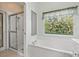 Elegant bathroom featuring a walk-in shower and a soaking tub with garden views at 8412 Whispering Woods Ct, Lakewood Ranch, FL 34202