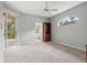Spacious bedroom with gray carpet and ceiling fan, featuring a glass slider and unique arched window at 8412 Whispering Woods Ct, Lakewood Ranch, FL 34202