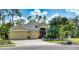 Yellow house with three-car garage, lush landscaping at 9351 Raes Creek Pl, Palmetto, FL 34221
