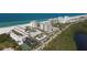 Breathtaking aerial view of a beachfront condo complex with lush greenery, tennis courts, and blue ocean at 2110 Benjamin Franklin Dr # 105, Sarasota, FL 34236
