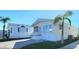 Front view of a tan mobile home with white trim and landscaping. Shows multiple mobile homes in a community at 3333 26Th E Ave # 1148, Bradenton, FL 34208