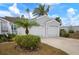 Two car garage with decorative landscape design including flowering plants, green shrubs, and palm trees at 502 Woodstork Cir, Bradenton, FL 34209