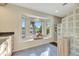 Sunlit bathroom showcasing a glass block shower, tiled floor, and a bay window with a view at 521 Cummings St, Sarasota, FL 34242