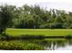 Golf course view with putting green, lush landscaping, and a serene water feature at 8325 Lindrick Ln, Bradenton, FL 34202
