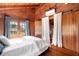 Cozy bedroom with wood walls, white bedding, and access to another room at 14900 Coker Gully Rd, Myakka City, FL 34251